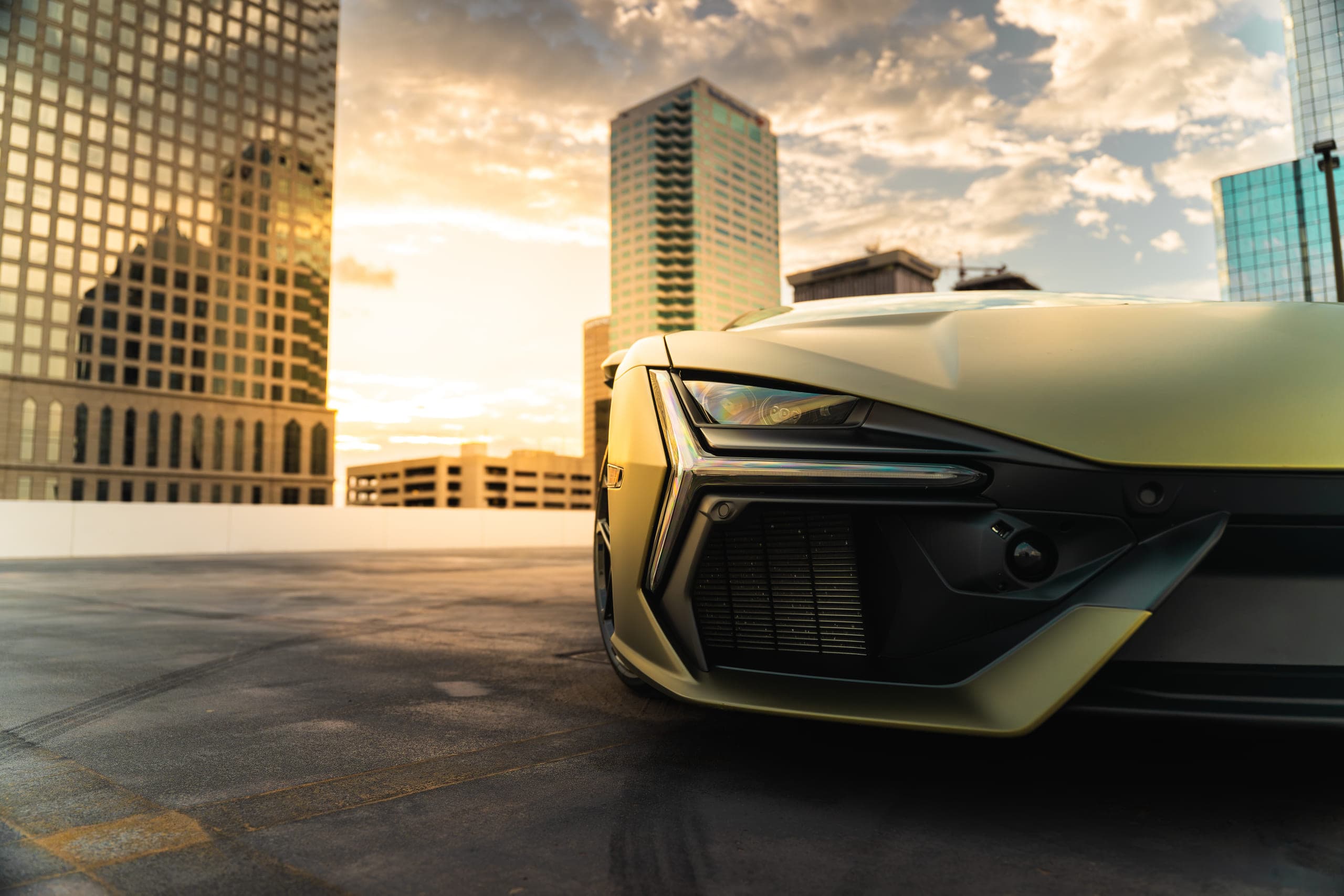A sports car photographed head on at dusk, skyline behind it