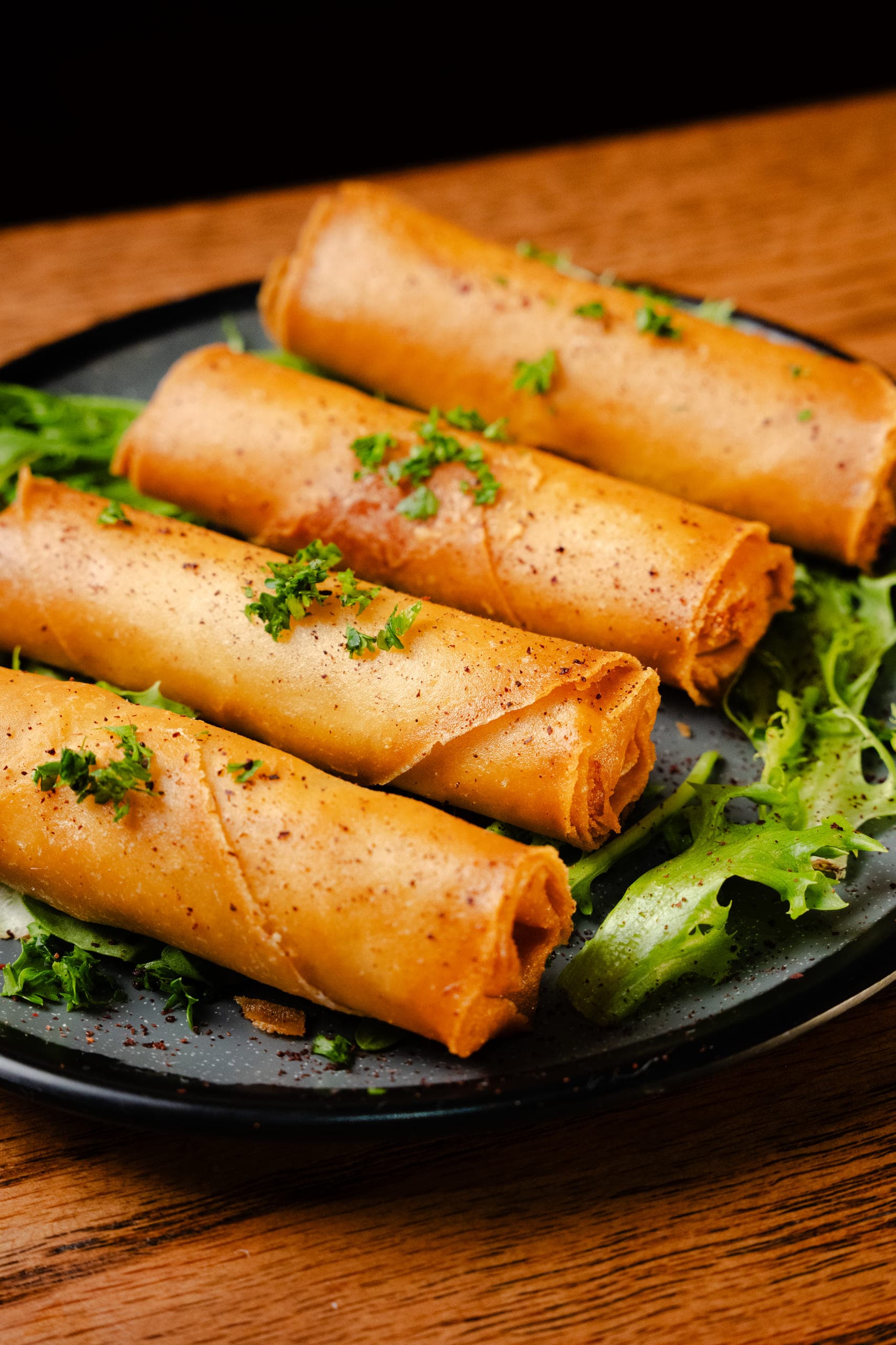 Cheese rolls lined up on a dark plate with herbs