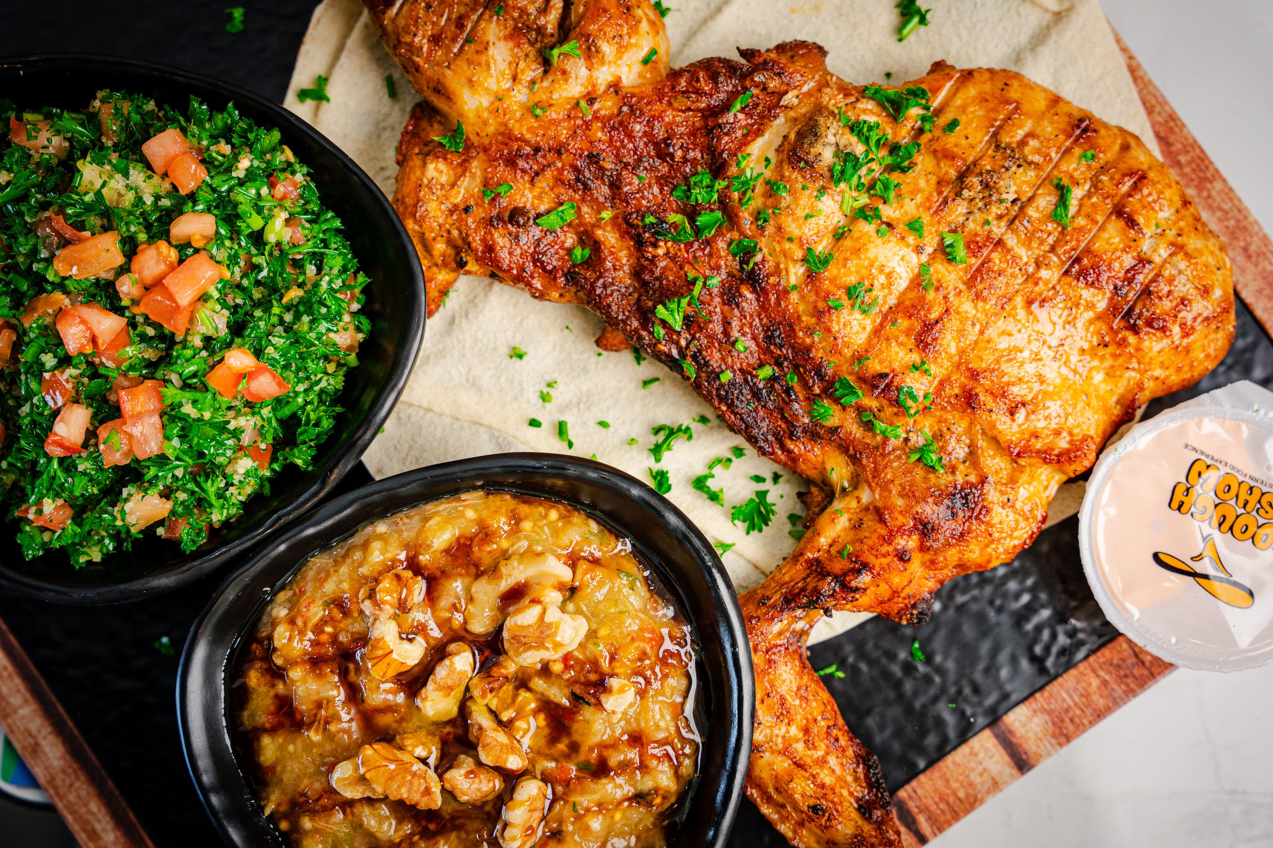 Grilled chicken platter with tabbouleh and dips, shot from above